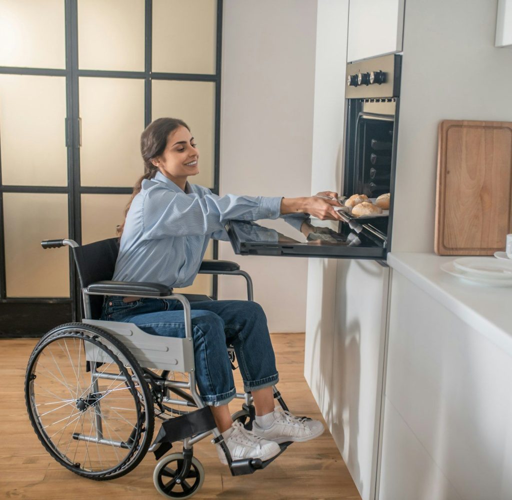 A young girl on a wheelchair doing some housework and looking involved